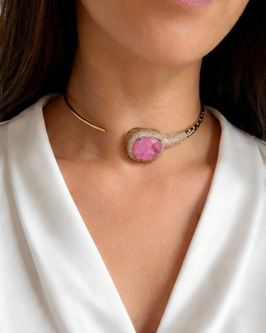 Necklace with a pink gemstone worn by a person in a white outfit